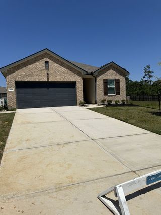A modern brick home featuring a spacious driveway in Idleloch by Starlight Homes, located in Huffman, TX.