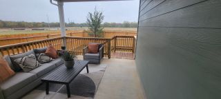 A cozy patio with stylish seating, modern table, and a view of the fenced-in backyard, perfect for outdoor relaxation.