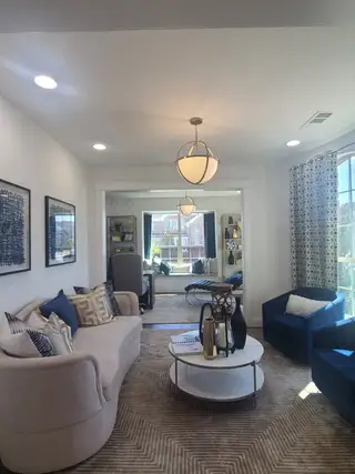 A cozy living room with stylish seating, elegant lighting, and a bright window view, creating a welcoming and comfortable space.