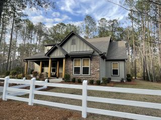 Street view Charming stone-accented home with a white fence in Carolina Bay by Center Park Homes (Ridgeville, SC).