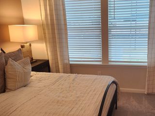 Model Home A beautifully decorated bedroom with soft tones, natural light, and plush furnishings, creating a cozy retreat.