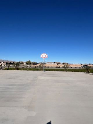 A spacious concrete basketball court under a clear blue sky in Windrose by Brightland Homes (Waddell, AZ).