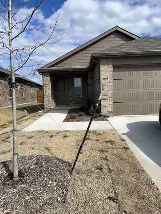 A single-story brick home with a covered entrance, front landscaping, and a driveway.