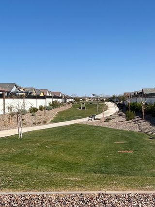 A serene community park with lush green lawns and walking paths in Anderson Farms: Premier by Lennar (Maricopa, AZ).