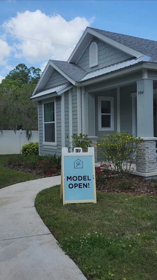 Street view A charming gray model home with a welcoming porch in Azalea Walk by Gallery Homes (Deland, FL).