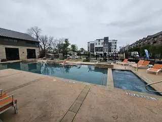 Community Amenities A modern pool area with lounging chairs in SoHo Square by Megatel Homes (Dallas, TX).