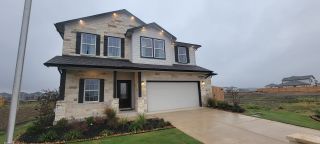 Charming stone home with black shutters and landscaped yard in Hennersby Hollow by CastleRock Communities (San Antonio, TX).