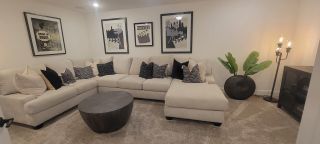 A cozy family room with a plush sectional, modern art, and chic decor accents, perfect for relaxing and entertaining.
