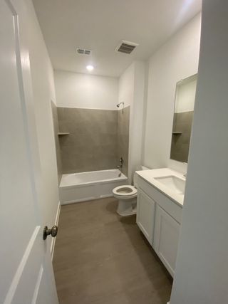 A modern bathroom featuring a sleek bathtub, white vanity, and neutral tile flooring.