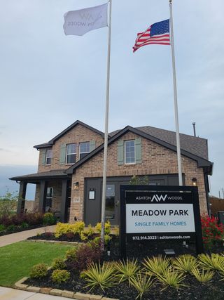 A charming brick home with green shutters and a manicured garden in Meadow Park by Ashton Woods (Melissa, TX).