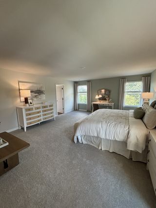 A spacious, cozy bedroom with plush carpet, elegant furniture, and soft lighting for a serene atmosphere.