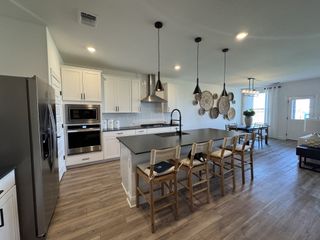 Model Home A modern kitchen with sleek black countertops, pendant lighting, wood accents, and artistic wall decor.