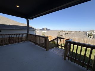 A covered backyard patio with wooden railings offers a scenic view of the neighborhood and a fenced yard for privacy.