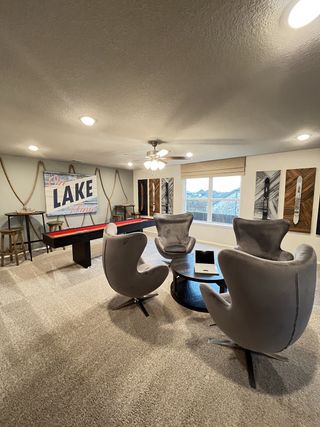 A cozy entertainment room featuring modern gray swivel chairs, a round table, and a shuffleboard game.