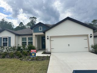 A charming beige home with blue accents and manicured landscaping in Westport Landing by LGI Homes (Jacksonville, FL).