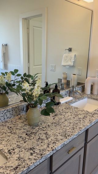 A contemporary bathroom vanity with sleek granite countertop, elegant fixtures, and a decorative floral arrangement.
