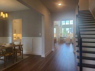 A modern open-concept living space with sleek wood flooring, elegant dining area, and bright natural lighting.