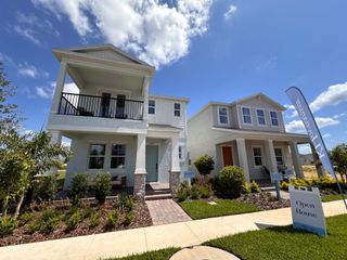 Two-story white homes with elegant balconies and lush landscaping in Osprey Ranch by K. Hovnanian® Homes (Winter Garden, FL).