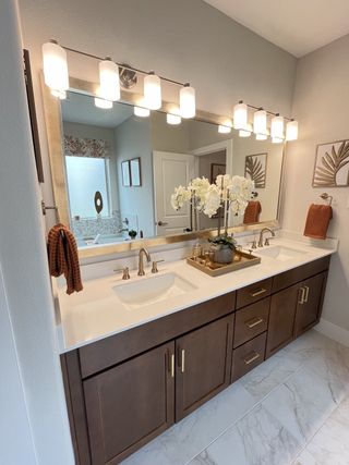 Elegant bathroom with a double vanity, modern lighting, and chic decor accents.