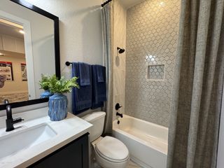 A stylish bathroom with a sleek vanity, geometric tile shower, and elegant black fixtures for a contemporary touch.