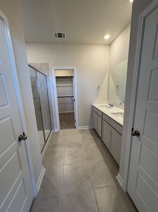 A luxurious bathroom with a double vanity, walk-in shower, and access to a generous walk-in closet.