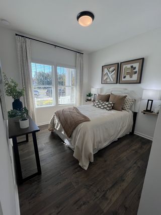 A cozy bedroom featuring elegant wood floors, stylish décor, and abundant natural light through large windows.