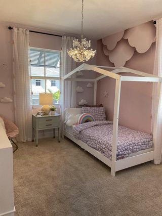 A dreamy pink-themed kids’ room with cloud accents, a house-frame bed, and a chandelier in Tuscan Springs by Lennar (Pembroke Pines, FL).
