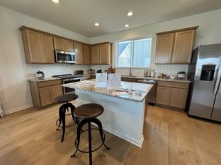 A modern kitchen with light wood cabinets, granite countertops, and a spacious island with bar stools.