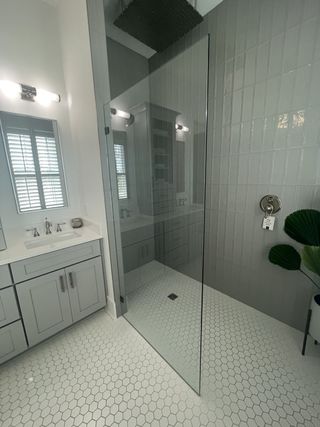 Model Home A sleek bathroom with hexagonal tiles, glass shower, and modern vanity, featuring elegant lighting and a minimalist design.