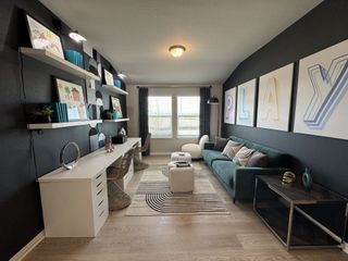 A stylish game room with dark walls, playful art, a cozy teal sofa, and sleek shelving, perfect for creativity and relaxation.