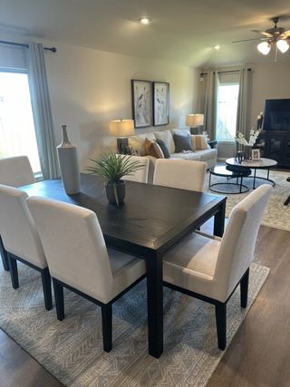 A contemporary dining and living area with elegant decor, featuring a dark wood table, plush chairs, and cozy lighting.