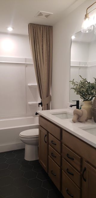 Model Home A cozy bathroom with hexagonal floor tiles, rustic wood vanity, and elegant lighting accents.