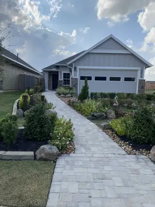 A charming home with brick accents and landscaped path in Robins Landing by Chesmar Homes (Houston, TX).