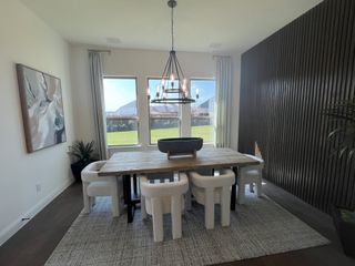 Model Home A sophisticated dining room with a rustic wooden table, plush seating, and accent wall.