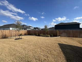 Model Home Well-maintained backyard with a fresh lawn, bordered by a wooden fence, offering privacy and tranquility.