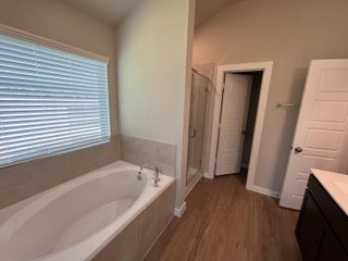 A cozy bathroom features a soaking tub, glass shower, and wood flooring, ideal for relaxing and rejuvenating.