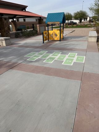 Community Amenities A charming community space with play equipment and hopscotch in Bridle Park at Alamar by Richmond American Homes (Avondale, AZ).