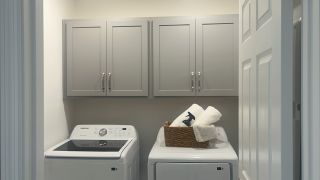 A functional laundry room with sleek gray cabinets, modern appliances, and organized storage solutions.