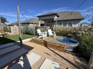 A charming backyard with seating, a stock tank pool, and string lights in the Lariat community by Landsea Homes (Liberty Hill, TX).