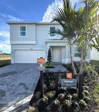 A modern two-story home with paver driveway and lush landscaping in Riverwood at Everlands by Lennar (Palm Bay, FL).