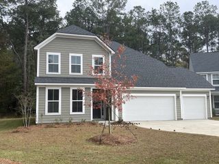 Street view A charming gray home with a spacious garage and a young tree in Enclave at South Pointe Estates by DRB Homes (Summerville, SC).
