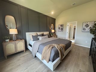 A cozy bedroom with a paneled accent wall, modern decor, and warm lighting, featuring wood flooring and stylish furnishings.