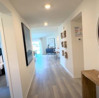 A bright, inviting hallway with modern decor and light wood flooring leading to an open living space.