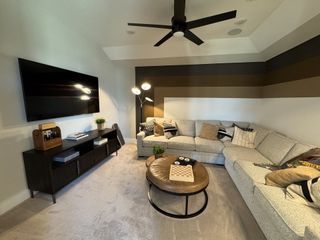 Model Home A cozy living room with neutral tones, featuring a sectional sofa, modern TV setup, and stylish decorative accents.