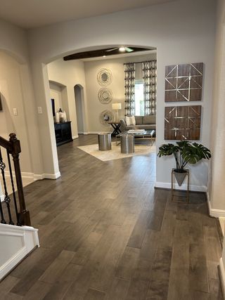Model Home A welcoming entrance leads to a modern living space with wood flooring, art pieces, and elegant decor.