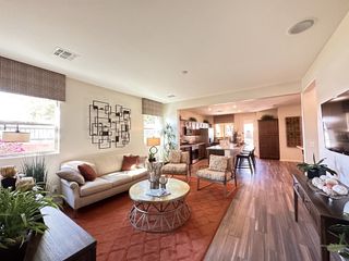 A cozy living room with patterned chairs, warm rug, and open layout leading to a modern kitchen.