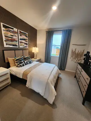 Model Home A cozy modern bedroom featuring textured walls, stylish artwork, soft lighting, and elegant furnishings.