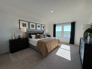 A spacious bedroom featuring a tufted headboard, elegant decor, and large windows inviting abundant natural light.