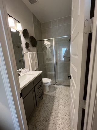 A modern bathroom featuring a sleek vanity, textured floor tiles, and a glass shower enclosure with contemporary lighting.