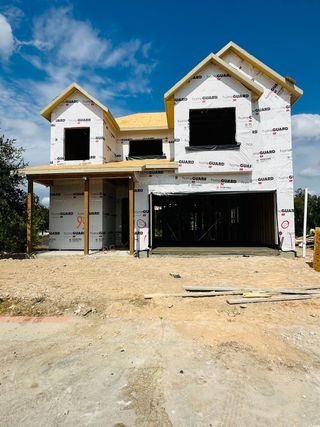Street view A contemporary two-story under construction in Cross Creek by Brohn Homes, Cedar Park, TX, with a pitched roof and spacious garage.